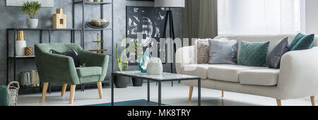 Table en métal avec des vases de verre debout dans télévision industrielle avec l'intérieur de la table lumineuse et fauteuil vert Banque D'Images