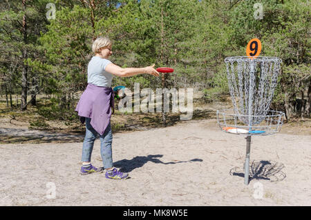 Femme jouant de disc golf sur le golf de disque Valgeranna en Estonie, jetant une battant disct au trou numéro 9 Banque D'Images