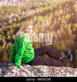 Jeune femme assise sur le bord de la falaise. Banque D'Images