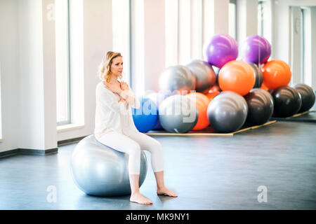 Jeune femme faisant de l'exercice avec un fitball dans une salle de sport. Banque D'Images
