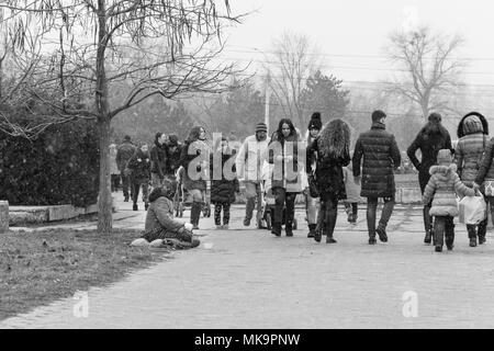 Un groupe de personnes marchant à travers un parc d'hiver, un reportage photo en noir et blanc. Banque D'Images