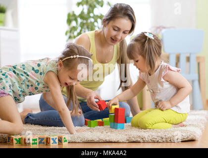 Adorables enfants jouant avec maman jouets colorés Banque D'Images