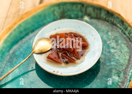 Confiture de Coing en petits blue plaque en céramique avec seaspoon doré placé sur une plaque en céramique turquoise plus grande. Banque D'Images