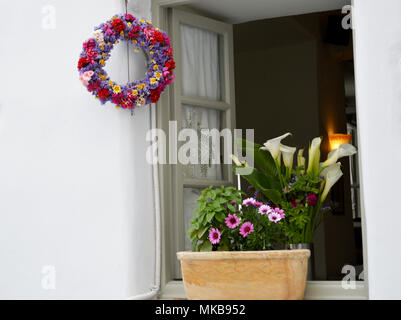 Une jolie fenêtre de la Grèce. Des fleurs colorées et de feuilles. Couronne de porte et fenêtre de décoration Banque D'Images