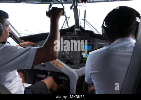 Vue du cockpit d'un petit avion volant dans le ciel. Équipe de pilotes sur avion ou hydravion, équipage touchant l'équipement et les commandes sur le tableau de bord Banque D'Images