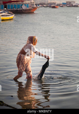 Une vieille dame se lave linge dans le Gange à Varanasi. Banque D'Images