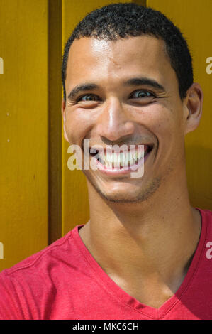 Portrait d'un homme afro-américain avec un grand sourire sur un mur jaune Banque D'Images