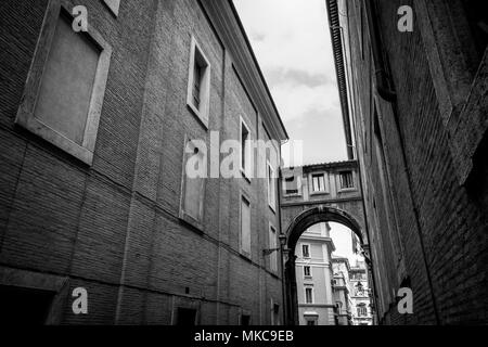 Un ancien arch connecte deux vieux bâtiments dans une rue de Rome, en noir et blanc Banque D'Images