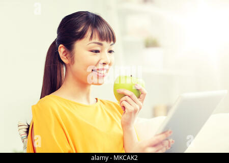 Happy asian woman with tablet pc et Apple à la maison Banque D'Images