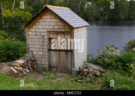 Hangar en bois et empilés, coupé du bois sur la rive au village historique de Kings Landing au Nouveau-Brunswick, Canada. Banque D'Images