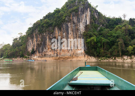 Bateau sur le fleuve Mékong en face d'une falaise de calcaire où les célèbres grottes de Pak Ou sont définis. Ils sont situés près de Luang Prabang au Laos. Banque D'Images