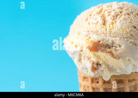 Boule de fonte délicieux Caramel au beurre salé le caramel Glace Vanille en cornet gaufré sur fond bleu. Sucreries Sucre d'indulgence de la toxicomanie Concept Banque D'Images