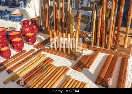 Tasses en céramique et de casseroles, sifflets en bois, instruments de musique en bois, de la rue du marché, des biens affichés sur la table. Banque D'Images