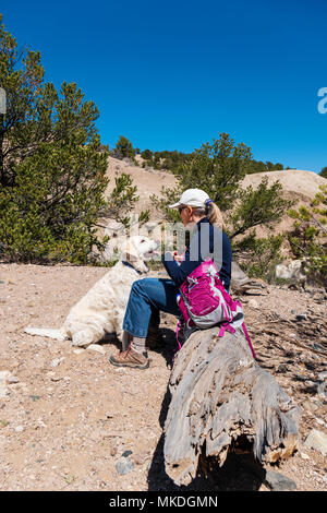 Female hiker avec chiens Golden Retriever de couleur platine marque une pause pour boire un verre Banque D'Images