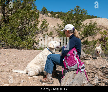 Female hiker avec chiens Golden Retriever de couleur platine marque une pause pour boire un verre Banque D'Images