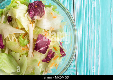 Salade fraîche dans un bol bleu sur fond de bois. Close-up Banque D'Images