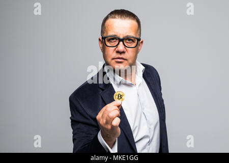 Close up portrait of a smiling man dressed in suit à la recherche d'or et de penser au bitcoin isolé sur fond blanc Banque D'Images