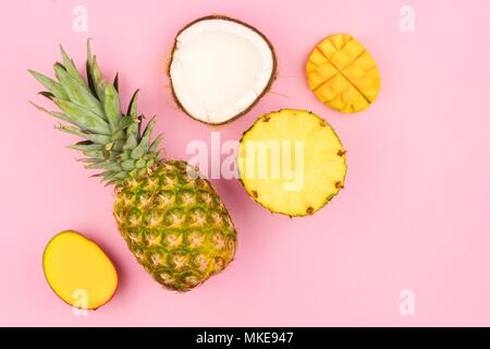 Mise à plat de fruits tropicaux avec de l'ananas, mangue et noix de coco sur un fond rose pastel. L'orientation d'angle. Banque D'Images