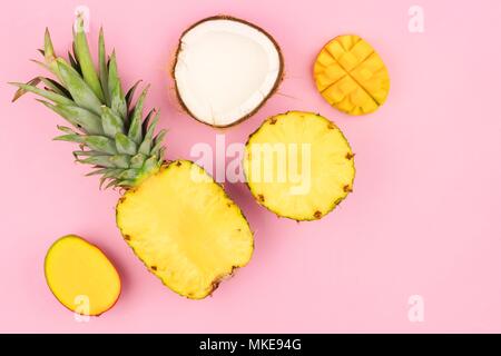 Mise à plat de fruits tropicaux avec de l'ananas, mangue et noix de coco sur un fond rose pastel. L'orientation d'angle. Banque D'Images