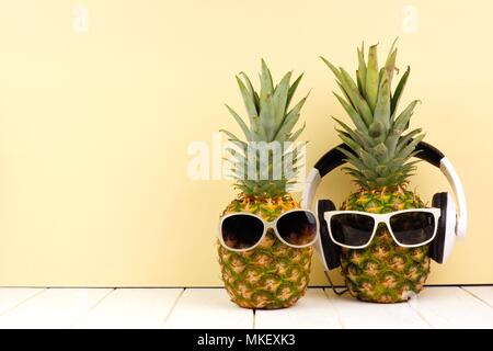 L'ananas avec des lunettes de Hipster et casque sur fond jaune. Concept d'été minime. Banque D'Images