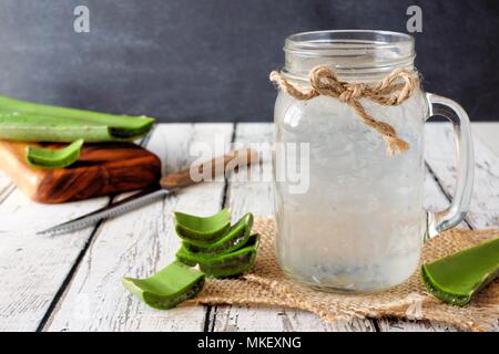 Jus d'Aloe vera sain dans un pot Mason en verre. Still Life, vue latérale sur le bois blanc. Banque D'Images