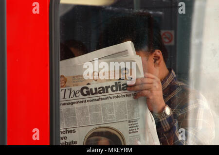 Libre d'hommes de banlieue bus lire le journal The Guardian sur un bus et faire une news rattraper Banque D'Images
