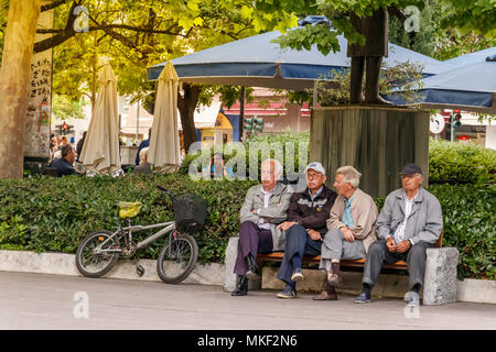 Larissa, Thessalie, Grèce - Mai 4th, 2018 : Quatre hommes assis dans une banque placés dans la Kentriki Platia (Place centrale) de la ville de Larissa, en Grèce. Banque D'Images