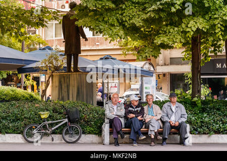 Larissa, Thessalie, Grèce - Mai 4th, 2018 : Quatre hommes assis dans une banque placés dans la Kentriki Platia (Place centrale) de la ville de Larissa, en Grèce. Banque D'Images