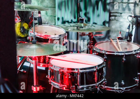 Kit de batterie avec des bâtons placés à l'extérieur avant une performance rock, feu rouge, Banque D'Images