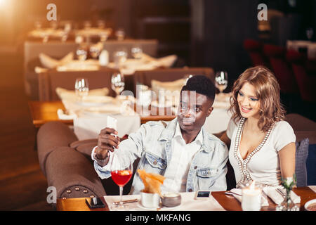 De race mixte attrayant couple en tenant à selfies bar vide attendant leur amis viennent Banque D'Images