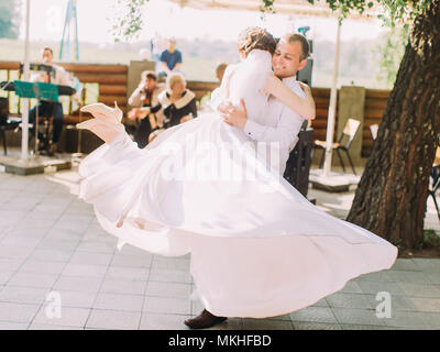 Marié est de faire tourner la belle mariée dans la longue robe de mariage. Banque D'Images