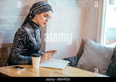 Arabian Woman working in coffee shop with digital tablet et boivent du café Banque D'Images