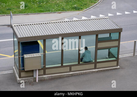 Vue en grand angle d'un homme vérifiant son téléphone portable en attendant à un arrêt de bus Banque D'Images