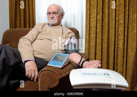 L'homme contrôle de sa pression artérielle à domicile avec un sphygmomanomètre électronique Banque D'Images