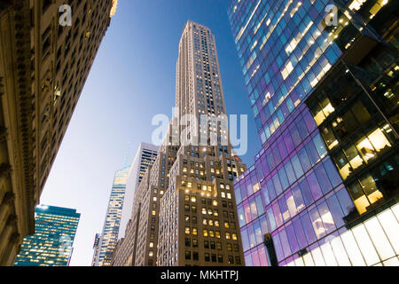 Vue depuis le bas vers le haut de certains des gratte-ciel de Manhattan au crépuscule, ciel bleu en arrière-plan. New York City, USA. Banque D'Images