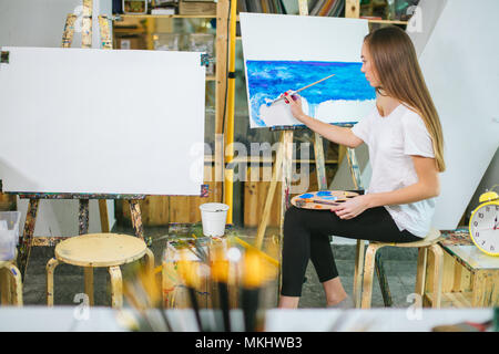 Femme artiste peint photo sur toile avec des peintures à l'huile dans son atelier Banque D'Images