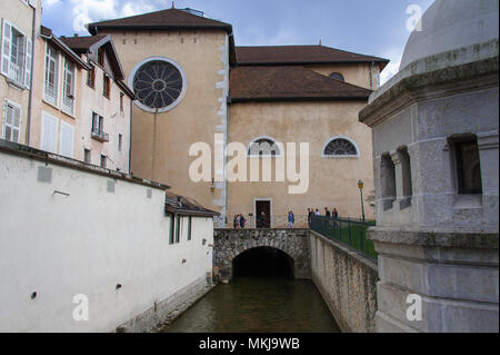 Les personnes qui traversent une passerelle au-dessus de la rivière Thiou, en face de l'église Sainte Jeanne de Chantal (église de St Joan) dans la vieille ville, Annecy. France Banque D'Images