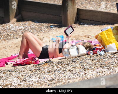 Minster sur mer, Kent, UK. 8 mai, 2018. Météo France : une chaude journée ensoleillée à Minster sur mer dans le Kent en tant que chef des gens à la plage. Une femme lit un Kindle tout en soleil. Credit : James Bell/Alamy Live News Banque D'Images