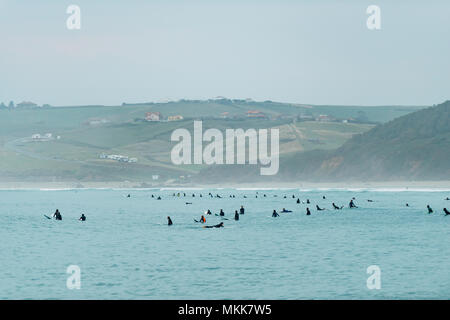 Beaucoup de surfeurs dans les vagues de la mer attendent pour rouler. San Vicente de la Barquera, Cantabrie, Espagne. Banque D'Images