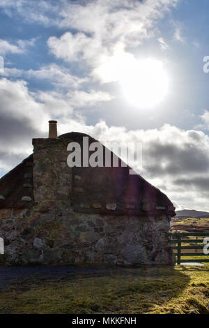 Hebridean blackhouse traditionnels de pignon avec toit de chaume - Ciel bleu et lens flare Banque D'Images