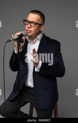 Homme d'âge moyen heureux et motivés, chanter une chanson avec un microphone, la présentation d'un événement ou d'avoir une partie, profiter de l'instant Banque D'Images