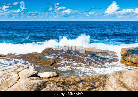 La vue imprenable sur le célèbre Coogee Beach à pied près de Bondi Beach, New South Wales, Australie. Vagues se brisant sur les rochers avec une belle bl Banque D'Images