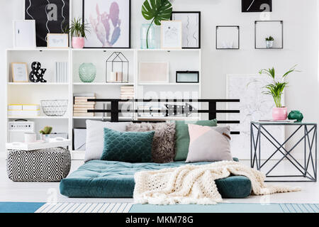 Pouf à motifs vert à côté du matelas dans une chambre lumineuse avec table sur des plantes d'intérieur Banque D'Images