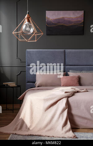 Lampe d'or au-dessus de lit dans une chambre élégante avec intérieur peinture sur mur gris violet Banque D'Images