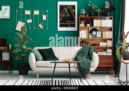 Concepteur, confortable salon intérieur avec un accueil bibliothèque, meubles anciens en bibliothèque, canapé beige et moderne, l'art abstrait sur un mur vert sarcelle Banque D'Images