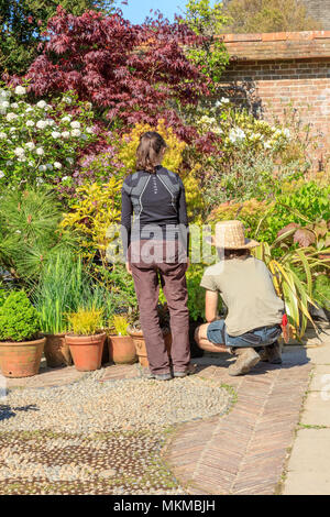 Deux jeunes jardiniers, un homme dans un chapeau de paille, et une femme, organisant les récipients prêts pour la maison de banque mai visiteurs à Great Dixter, Rye, East Sussex, UK Banque D'Images