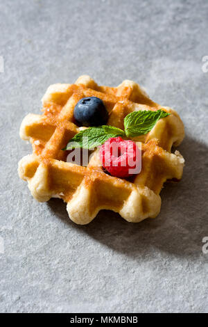 Gaufres Belges traditionnelles avec les bleuets et framboises sur la pierre grise Banque D'Images