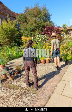 Deux jeunes jardiniers, un homme dans un chapeau de paille, et une femme, organisant les récipients prêts pour la maison de banque mai visiteurs à Great Dixter, Rye, East Sussex, UK Banque D'Images