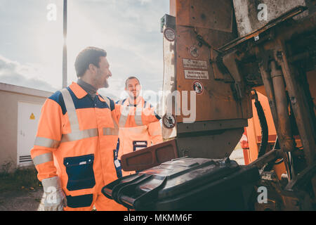 Deux garbagemen travaillant ensemble sur le vidage de poubelles Banque D'Images