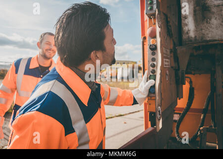 Deux garbagemen travaillant ensemble sur le vidage de poubelles Banque D'Images